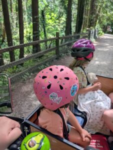 Two children in a cargo bike on a trail
